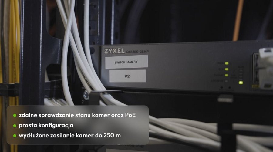 Zbliżenie na przełącznik Zyxel GS1350 w serwerowni, w lewym dolnym rogu napisane od punktorów: zdalne sprawdzanie stanu kamer oraz PoE, prosta konfiguracja, wydłużone zasilanie kamer do 250 m
